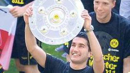 Zwei Hände an der Schale. Sahin hatte großen Anteil am Meistertitel des BVB. Foto: dpa
