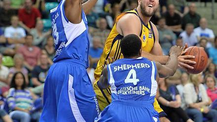 Der Berliner Miroslav Raduljica (M) spielt gegen die Frankfurter Roger Powell (L) und Jevohn Shepherd. 