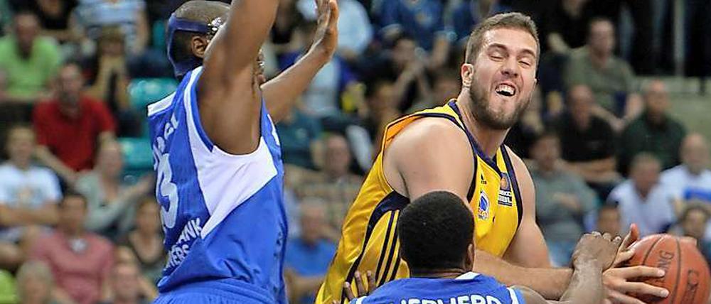 Der Berliner Miroslav Raduljica (M) spielt gegen die Frankfurter Roger Powell (L) und Jevohn Shepherd. 