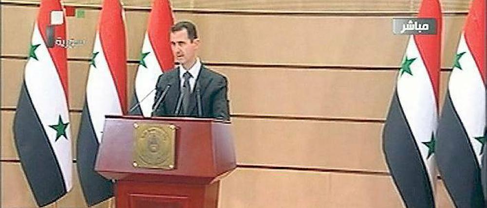 Als Vater der Nation mit einer Reihe von Landesflaggen im Rücken inszenierte sich Baschar al Assad bei seiner Rede – hier eine Aufnahme von der Fernsehübertragung. Foto: rtr