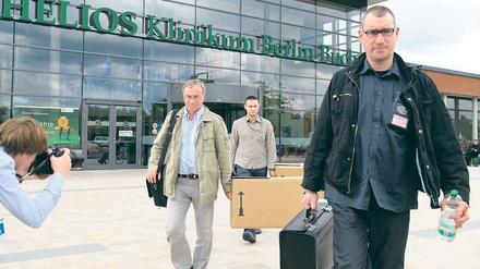Genau untersucht. Ermittler tragen am Dienstag sichergestellte Unterlagen aus der Helios-Klinik in Buch. Auch Privatwohnungen von verdächtigen Ärzten und Geschäftsführern wurden von der Polizei überprüft. 