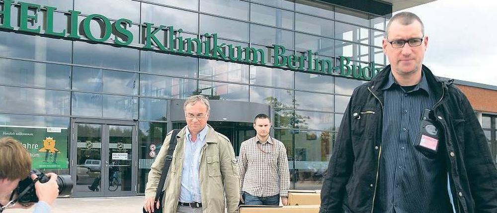 Genau untersucht. Ermittler tragen am Dienstag sichergestellte Unterlagen aus der Helios-Klinik in Buch. Auch Privatwohnungen von verdächtigen Ärzten und Geschäftsführern wurden von der Polizei überprüft.