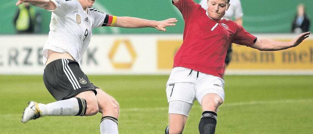 Haltung bewahren. Birgit Prinz (l.), hier im Zweikampf mit Norwegens Trine Rönning, trotzt derzeit noch der Konkurrenz von der deutschen Bank. Foto: dpa