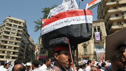 Dieser Demonstrant hat sich ein Schiff aus Pappe in den Farben Ägyptens auf den Kopf geschnallt. „Wir müssen wieder auf den richtigen Kurs“, sagt er. 