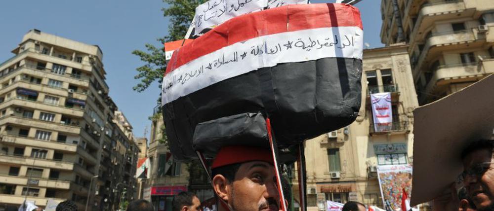 Dieser Demonstrant hat sich ein Schiff aus Pappe in den Farben Ägyptens auf den Kopf geschnallt. „Wir müssen wieder auf den richtigen Kurs“, sagt er.