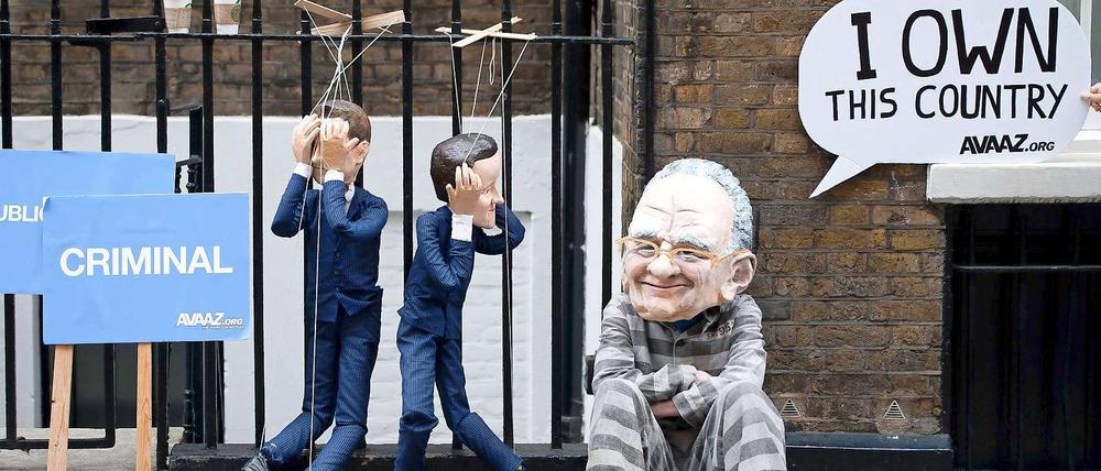 Der britische Premier Cameron und Kulturminister Jeremy Hunt als Marionetten, Medienmogul Rupert Murdoch in Gefangenenkleidung: Protestaktion in London.