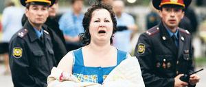 Eine Überlebende des Unglücks irrt nach ihrer Rettung fassungslos umher. Foto: Reuters