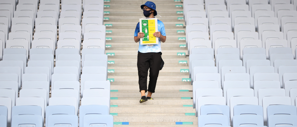 Neuer olympischer Dreikampf: Ein Volunteer erinnert im fast leeren Stadion von Miyagi an das Maskentragen, Händewaschen und Abstandhalten. Foto: Molly Darlington/Reuters