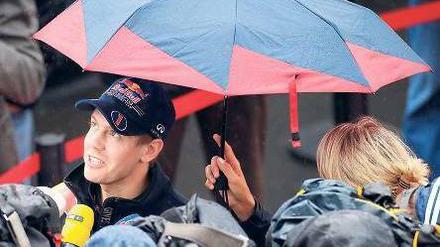 Interviews im Regen. Weltmeister Sebastian Vettel kommt kaum noch zur Ruhe – das gilt auch für viele andere Formel-1-Rennfahrer. Foto: dapd