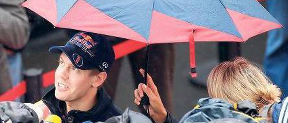 Interviews im Regen. Weltmeister Sebastian Vettel kommt kaum noch zur Ruhe – das gilt auch für viele andere Formel-1-Rennfahrer. Foto: dapd