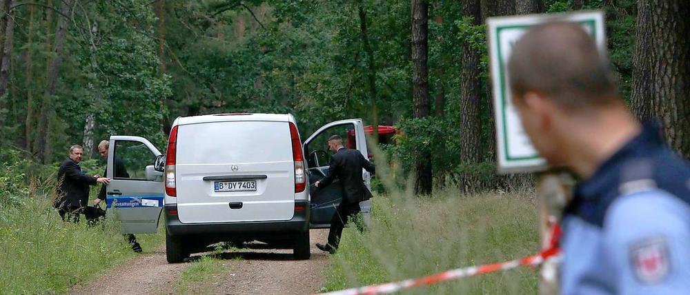 Ein Leichenwagen steht am Freitag in einem abgesperrten Waldstück bei Börnicke (Havelland). Zwei tote Kinder waren in einem ausgebrannten Auto gefunden worden.