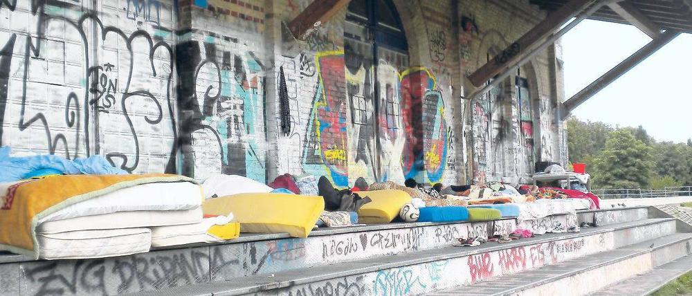 Provisorisches Zuhause. Hier leben die rumänischen Familien im Görlitzer Park. Nebenan sitzen Gäste im Café. 