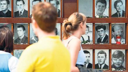 An der Gedenkstätte. Besucher sehen sich am 50. Jahrestag des Mauerbaus Fotos von Todesopfern an, die bei der Flucht von Ost nach West ums Leben kamen. Foto: Clemens Bilan/dapd