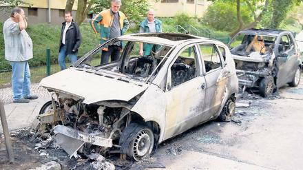 Anwohner stehen am Morgen danach ratlos vor zwei abgebrannten Wagen in Westend. Betroffen waren in der Reußallee eine A-Klasse von Mercedes und ein Smart.