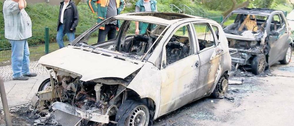 Anwohner stehen am Morgen danach ratlos vor zwei abgebrannten Wagen in Westend. Betroffen waren in der Reußallee eine A-Klasse von Mercedes und ein Smart.