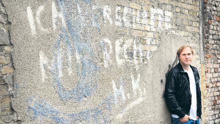 Kunst am Bau. Sänger Thees Uhlmann vor graffitiverzierter Friedhofsmauer.
