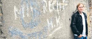 Kunst am Bau. Sänger Thees Uhlmann vor graffitiverzierter Friedhofsmauer.