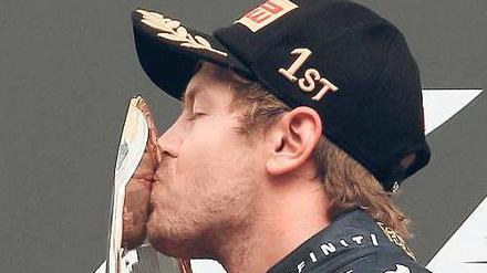 Auf Schmusekurs. Sebastian Vettel kann sich mit der Trophäe für den Sieg in Spa offensichtlich anfreunden. Foto: dapd
