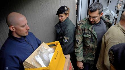 Ermittler kommen mit beschlagnahmten Materialien aus der Wohnung eines der Verdächtigen.