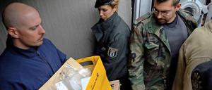 Ermittler kommen mit beschlagnahmten Materialien aus der Wohnung eines der Verdächtigen.