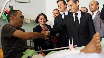 David Cameron (li.) besucht mit Nicolas Sarkozy einen Verletzten in einem Krankenhaus in Tripolis.