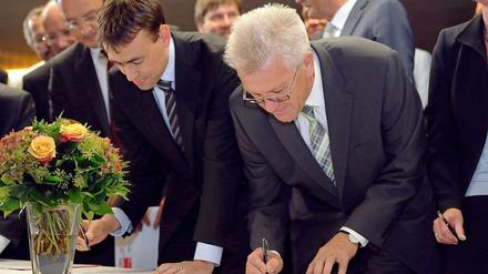 Schwarz auf Weiß. Nils Schmid (SPD) und Winfried Kretschmann (Bündnis 90/Die Grünen), unterschreiben den Antrag zur Volksabstimmung. 