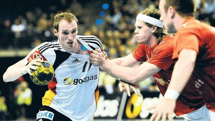 Schweres Durchkommen. Holger Glandorf (links) wird hier attackiert vom Dänen Mikkel Hansen. Foto: dpa