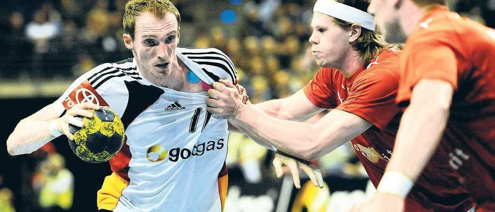 Schweres Durchkommen. Holger Glandorf (links) wird hier attackiert vom Dänen Mikkel Hansen. Foto: dpa