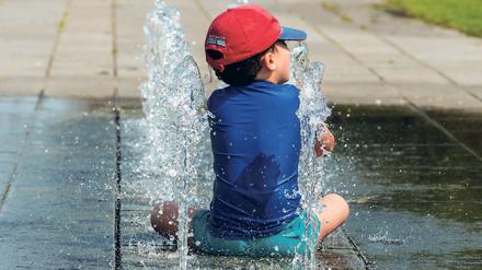 Ein Junge erfrischt sich am 04.07.2015 in Berlin an einem Brunnen im Regierungsviertel. Bei den hochsommerlichen Temperaturen zog es dennoch viele Menschen ins Freie. Foto: Paul Zinken/dpa +++(c) dpa - Bildfunk+++