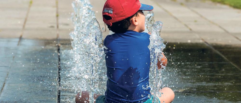 Ein Junge erfrischt sich am 04.07.2015 in Berlin an einem Brunnen im Regierungsviertel. Bei den hochsommerlichen Temperaturen zog es dennoch viele Menschen ins Freie. Foto: Paul Zinken/dpa +++(c) dpa - Bildfunk+++