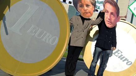 Zerrbilder aus Pappmaché: Im Oktober 2011 stehen Demonstranten mit Merkel- und Sarkozy-Masken vor dem Berliner Kanzleramt.