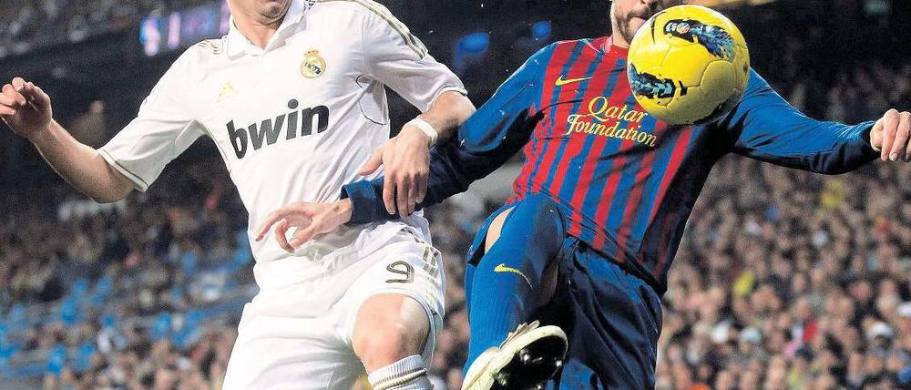 Raus aus der Illegalität, rauf aufs Trikot. Private Wettanbieter wie Bwin könnten künftig nicht nur auf den Hemden von Real Madrid (hier Karim Benzema gegen Barcelonas Gerard Piqué), sondern auch in der Bundesliga werben. Foto: Reuters