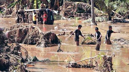 Katastrophengebiet Mindanao. Bewohner waten durch den Schlamm, den die Sturzflut hinterlassen hat. Fotos: dpa(2)