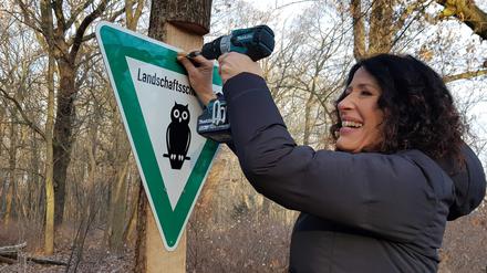 Umweltsenatorin Bettina Jarasch montiert das erste Schild im neuen Landschaftsschutzgebiet.