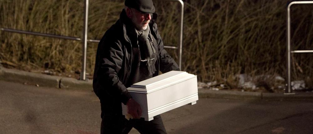 Schwerer Gang: Ein Bestatter trägt den kleinen Kindersarg zu seinem Fahrzeug.