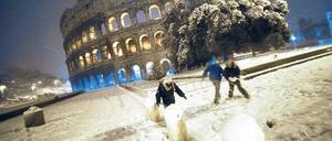 Winternacht in Rom. Kinder bauen Schneemänner vor dem Kolosseum. 