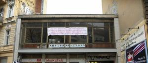 Das Banner an der Hausfassade ist weithin sichtbar. Immer wieder bleiben Passanten stehen und lesen, was in roten Buchstaben auf weißem Grund über ihren Köpfen prangt.