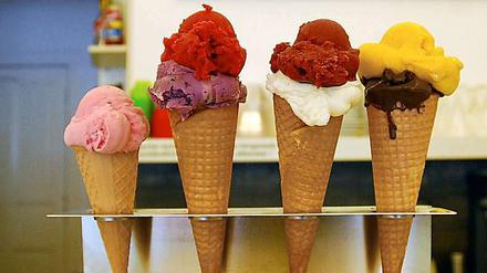 Eiswaffeln mit bunten Eiskugeln gefüllt und aufgereiht auf einem Tresen.
