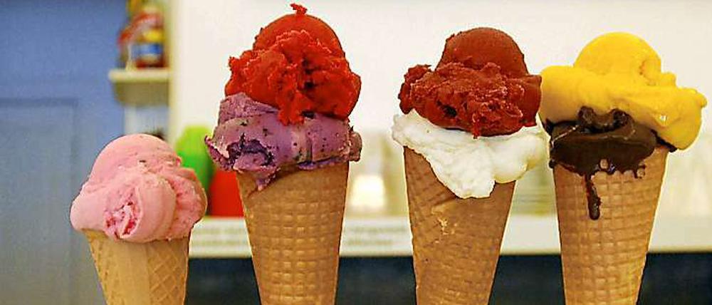 Eiswaffeln mit bunten Eiskugeln gefüllt und aufgereiht auf einem Tresen.