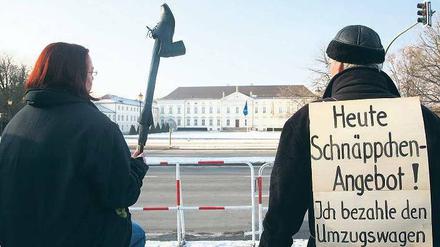 Hinterm Gitter. Vor dem Amtssitz des Bundespräsidenten protestieren Demonstranten gegen Christian Wulff. Nach arabischer Sitte wurde ihm der Schuh gezeigt. Das gilt als Zeichen der Verachtung. Foto: dpa/Stephanie Pilick