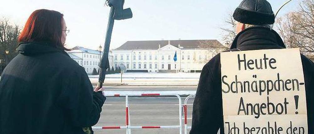 Hinterm Gitter. Vor dem Amtssitz des Bundespräsidenten protestieren Demonstranten gegen Christian Wulff. Nach arabischer Sitte wurde ihm der Schuh gezeigt. Das gilt als Zeichen der Verachtung. Foto: dpa/Stephanie Pilick