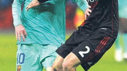 Nur gucken, nicht anfassen. Barcelonas Attraktion Lionel Messi (links) erwehrt sich der Avancen des Leverkuseners Daniel Schwaab. Foto: AFP