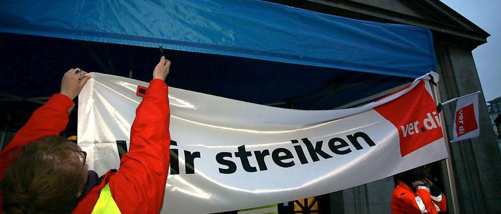 Streikposten hängen vor der U-Bahnstation Wittenbergplatz Transparente auf.