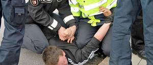 Polizisten nehmen einen gewalttätigen Demonstranten fest.
