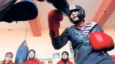 Mädchen in den Ring. Sadaf Rahimi mit ihrem Trainer in ihrem Kabuler Fitnesscenter. An der Wand stehen andere Frauen, die ebenfalls zum Boxen kommen. Foto: Omar Sobhani, Reuters