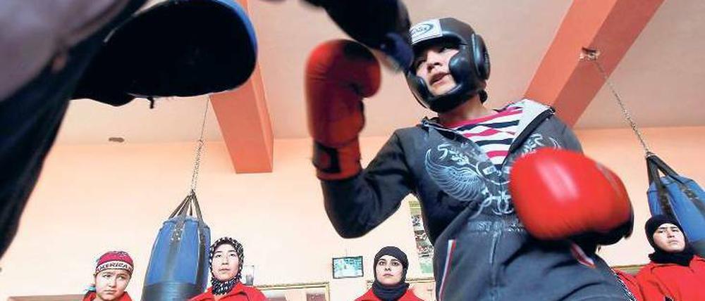 Mädchen in den Ring. Sadaf Rahimi mit ihrem Trainer in ihrem Kabuler Fitnesscenter. An der Wand stehen andere Frauen, die ebenfalls zum Boxen kommen. Foto: Omar Sobhani, Reuters