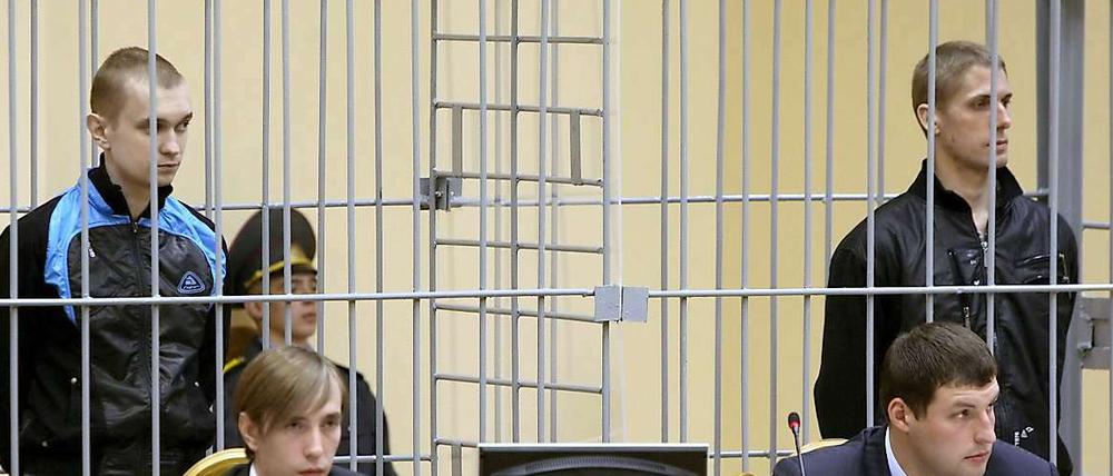 Die beiden Verurteilten Wladislav Kowaljow (rechts) und Dmitri Konowalow stehen am 15.09.2011 in einem vergitterten Käfig im Minsker Justizpalast. 