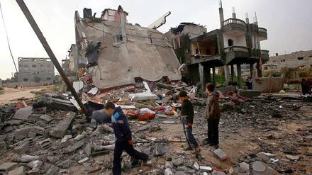 Kinder stehen vor einem von israelischen Luftangriffen zerstörten Gebäude im Gazastreifen. Nun sollen die Waffen ruhen.