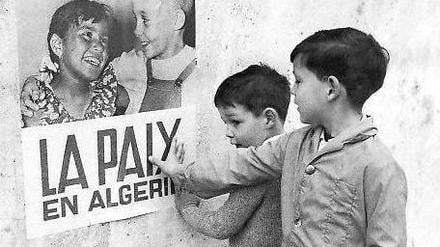 19. März 1962. Kinder in Algier vor einem Plakat der französischen Kolonialmacht, das den seit 16.06 Uhr geltenden Waffenstillstand verkündet. Foto: AFP