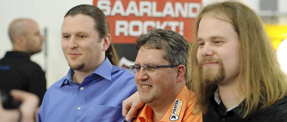 Gewinnertypen. Der Schatzmeister der Piratenpartei im Saarland, Andreas Augustin (v.l.), Michael Neyses (Piratenpartei) und der Beisitzer im Vorstand der Piratenpartei im Saarland, Michael Hilberer, posieren am Sonntagin Saarbrücken nach der Bekanntgabe der ersten Prognosen.